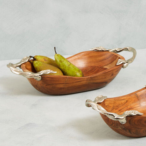 Two wooden bowls with silver handles on a light gray background