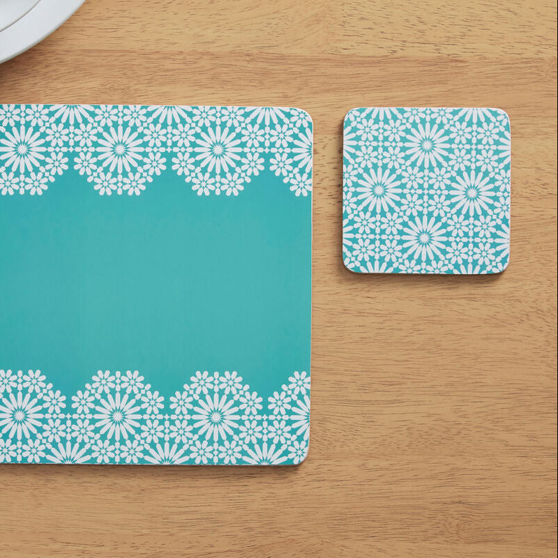 Teal placemat with white lace pattern on a wooden table
