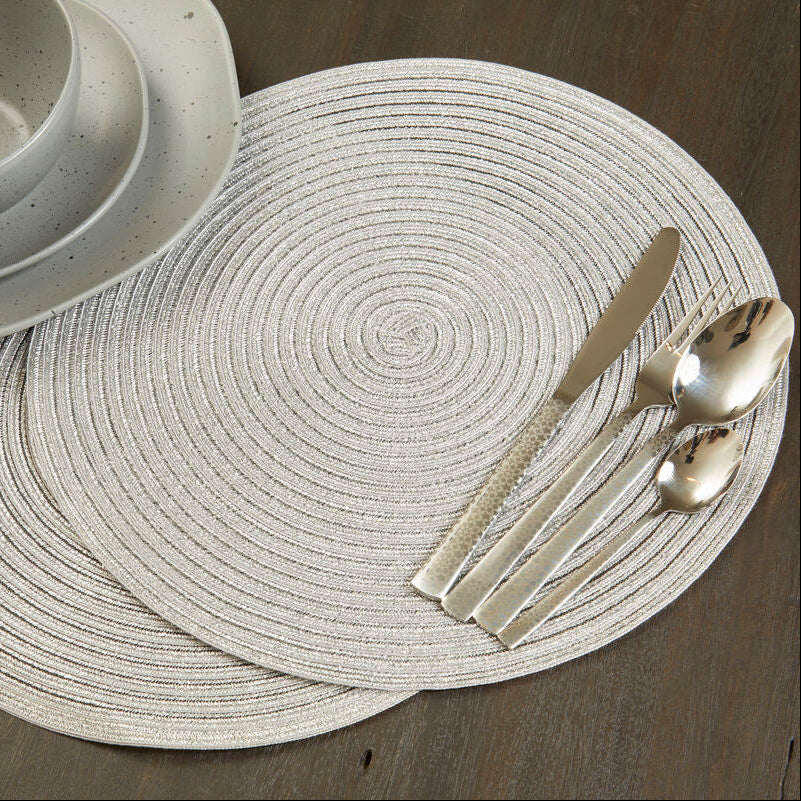 Round woven placemat with cutlery on a wooden surface