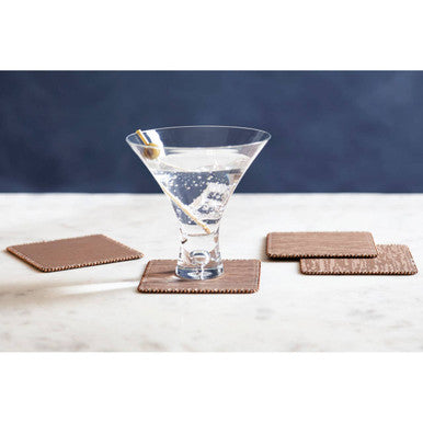 Martini glass with a cocktail on a white surface with brown coasters