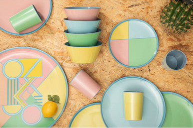 Colorful ceramic plates and bowls on a wooden surface with a cactus plant.