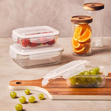 Glass food storage containers with wooden lids on a neutral background