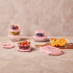 Set of pink kitchen containers with food on a neutral background