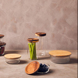 Set of glass containers with wooden lids on a wooden surface with a neutral background