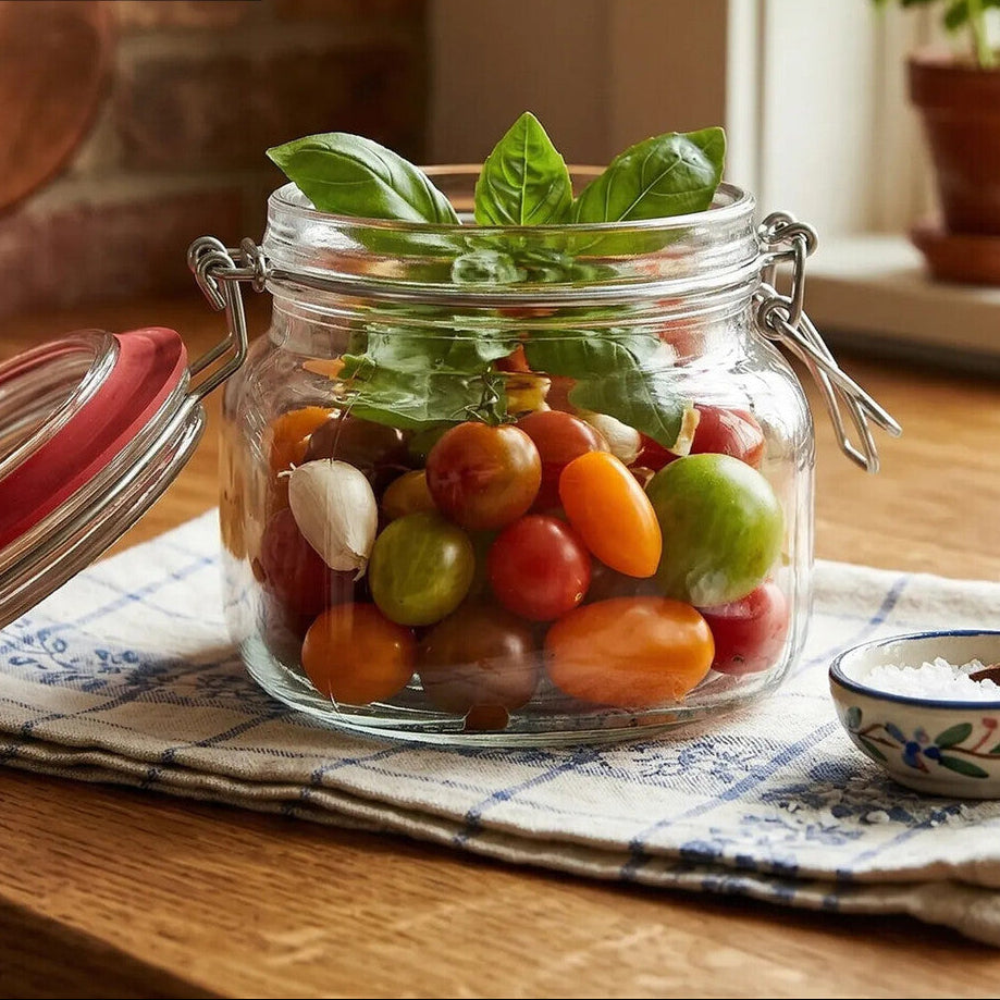 Glass jar with cherry tomatoes and basil leaves on a wooden table, with &
