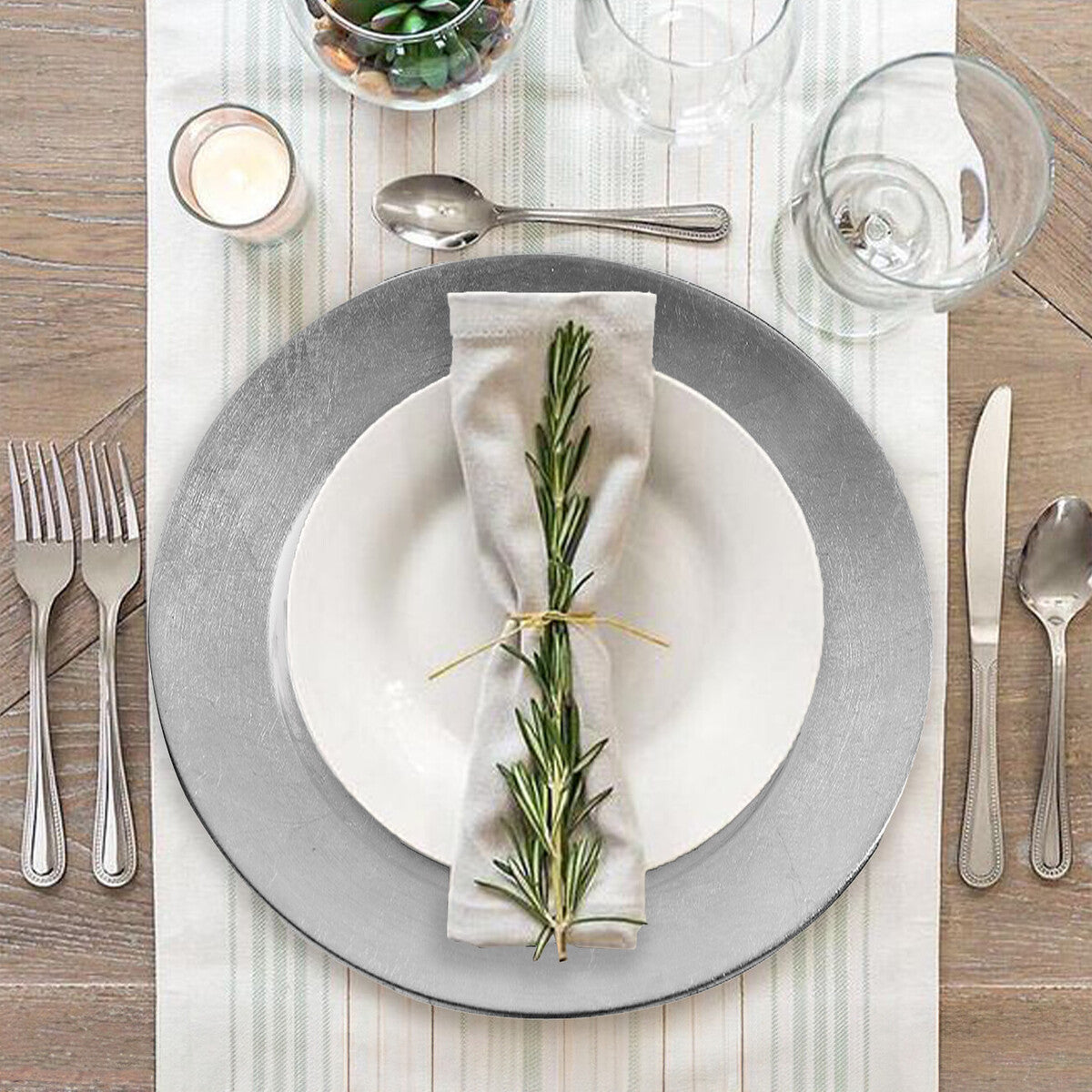 Elegant table setting with gray plates, white napkin, and rosemary on a wooden table.