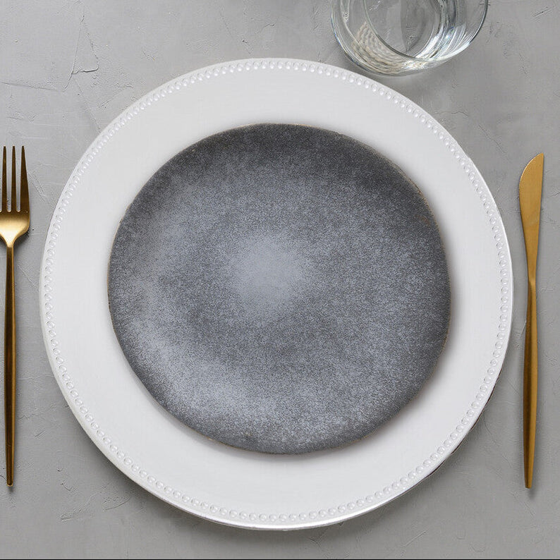 Set table with gray plates, gold cutlery, and autumn decorations on a gray surface.