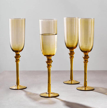 Set of four gold-rimmed wine glasses on a light gray surface with a neutral background