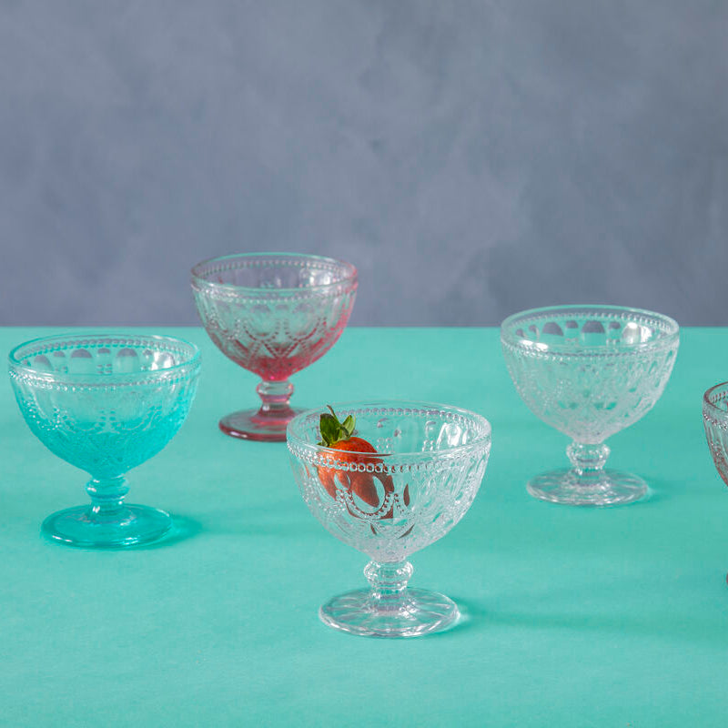 Set of vintage glass dessert bowls on a teal surface with a gray background