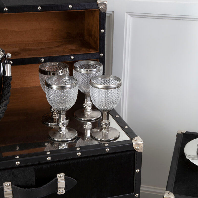 Decorative black chest with silver accents and crystal goblets on top.