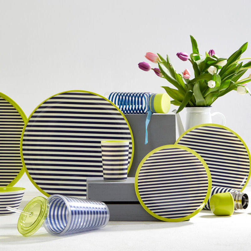 Striped ceramic plates and bowls with a vase of flowers on a white surface