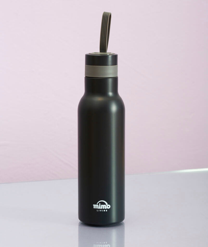 Black water bottle with a straw lid on a light pink background