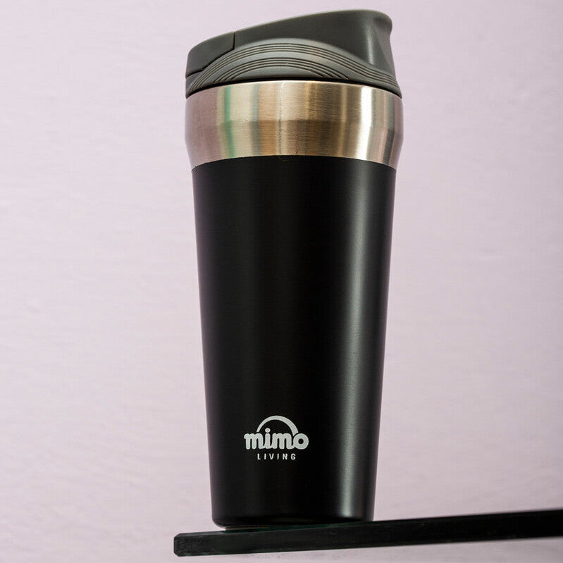Black insulated travel mug with silver lid on a light purple background