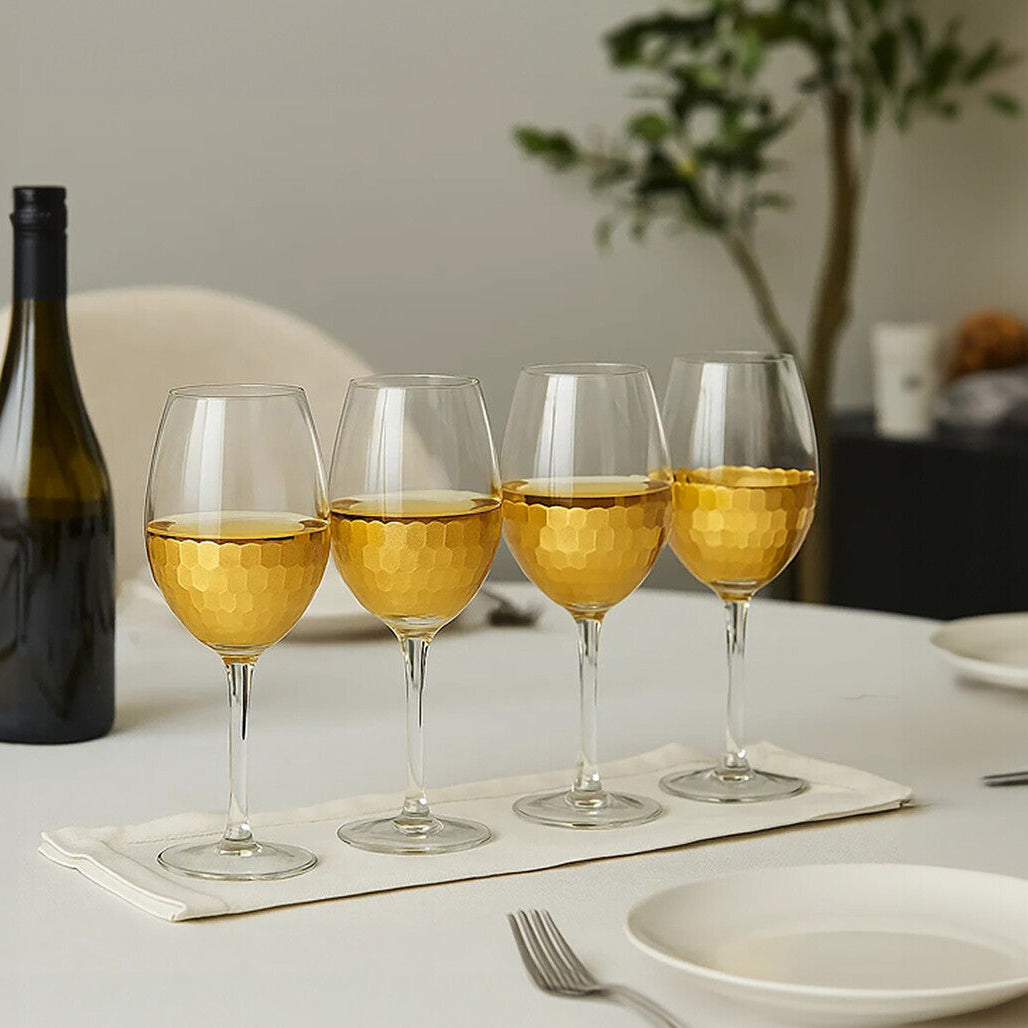 Wine bottle and four wine glasses with white wine on a table.