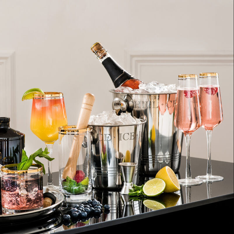 Beverage setup with cocktails, bottles, and bar tools on a tray.