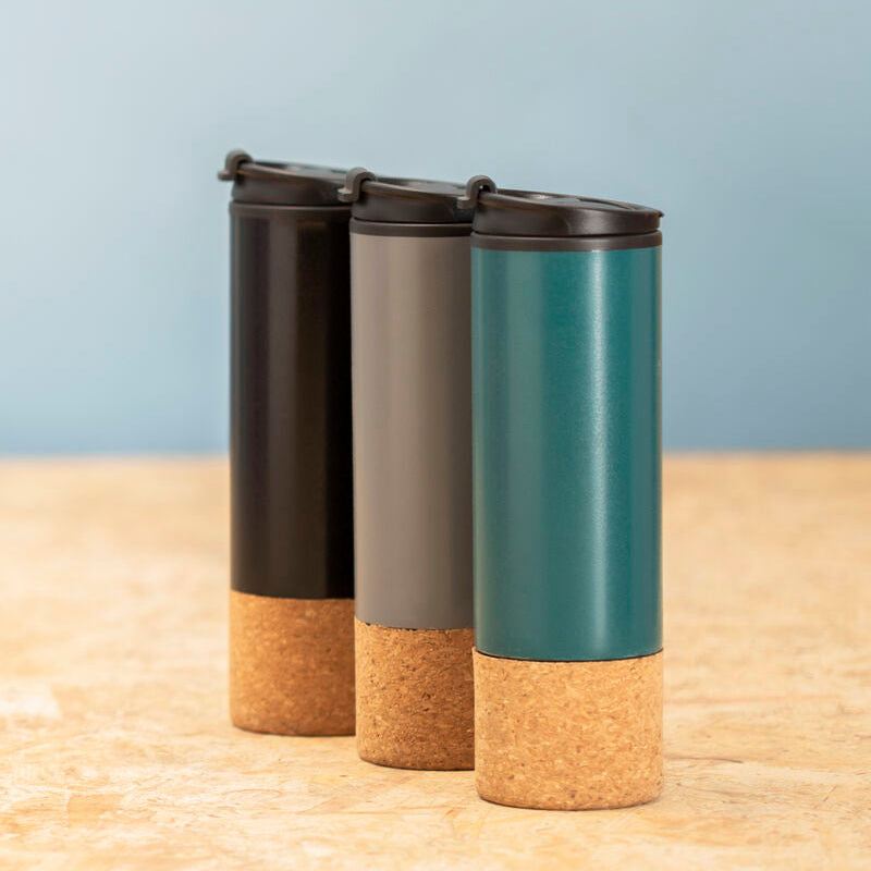 Three cylindrical containers with cork bases on a wooden surface and light blue background