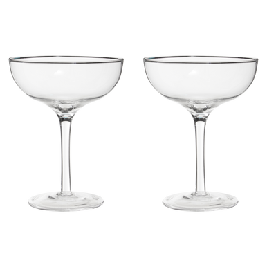 Two clear glass coupe glasses on a white background