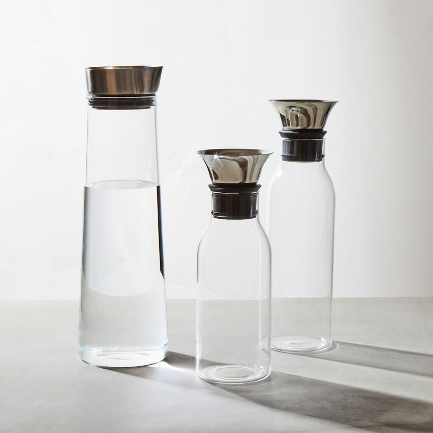 Three glass carafes with metal lids on a light gray background
