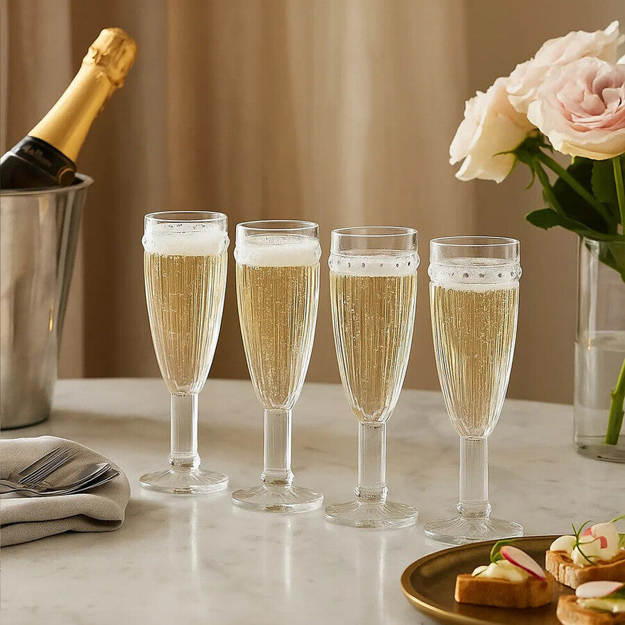 Set of champagne flutes with a bottle and flowers on a table