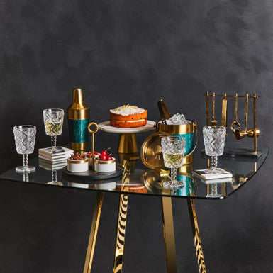 Decorative table setting with glasses, cake, and bottles against a dark background