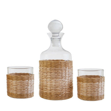 Decorative glass decanter with wicker accents and matching glasses on a white background