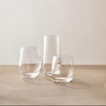 Three clear glass tumblers on a wooden surface with a plain background
