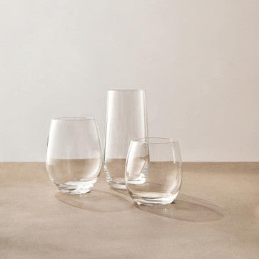 Three clear glass tumblers on a wooden surface with a plain background
