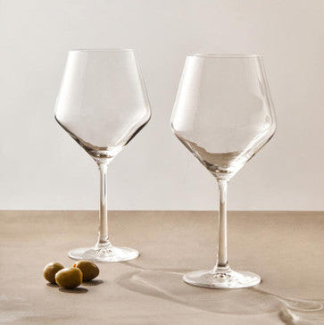 Two clear wine glasses on a neutral surface with a light background