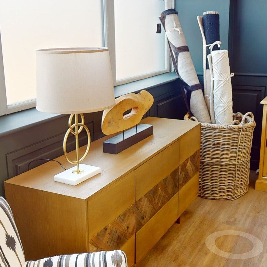 Wooden sideboard with lamp and decorative items next to a window