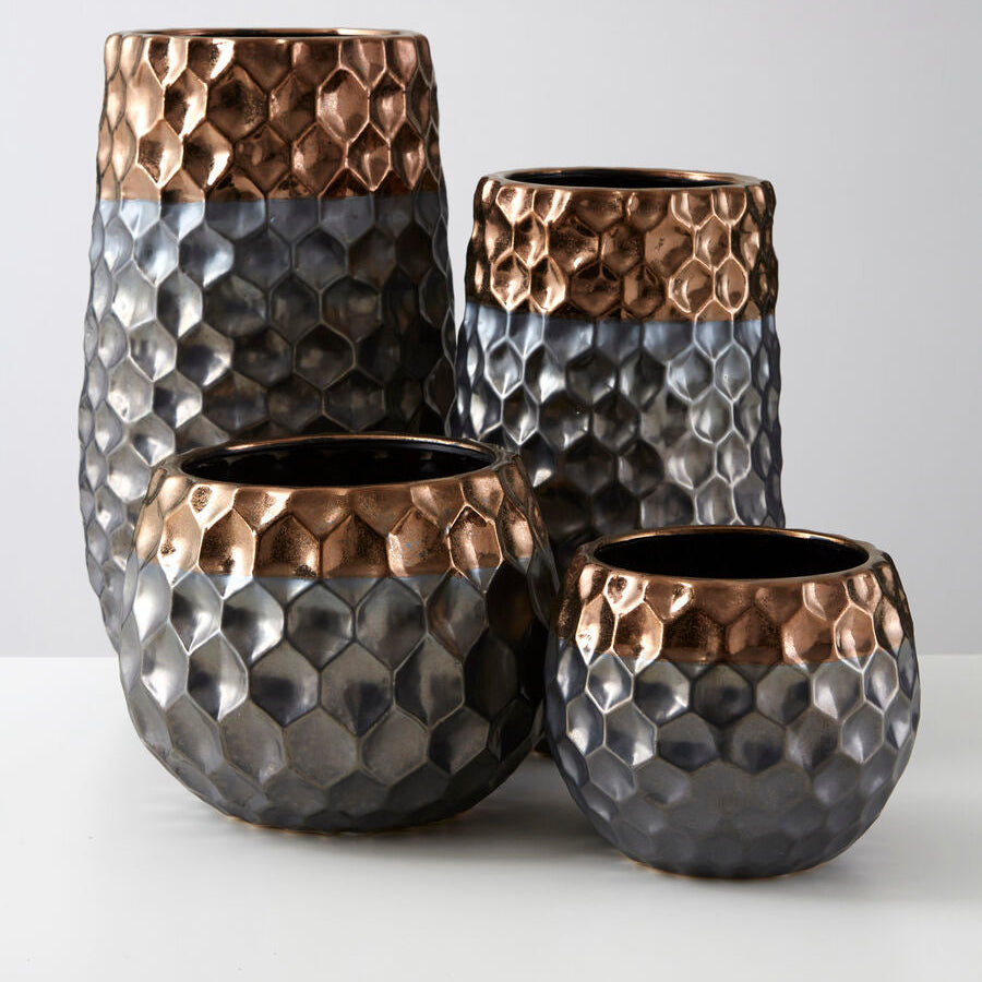 Set of four metallic vases with honeycomb pattern on a white background