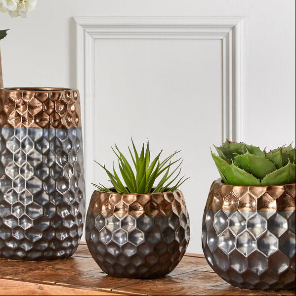 Set of three decorative vases with textured surfaces on a wooden surface.