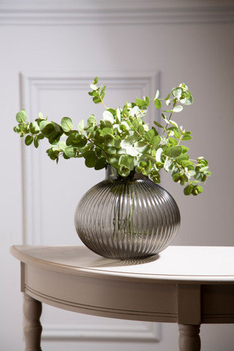 Decorative vase with greenery on a table against a neutral wall