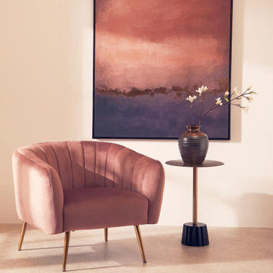 Pink armchair in a room with a large abstract painting on the wall.