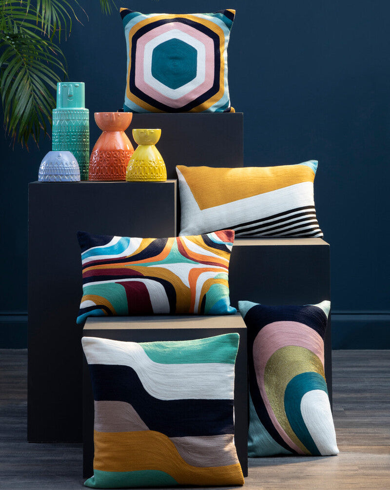 Colorful patterned cushions on a dark blue wall background