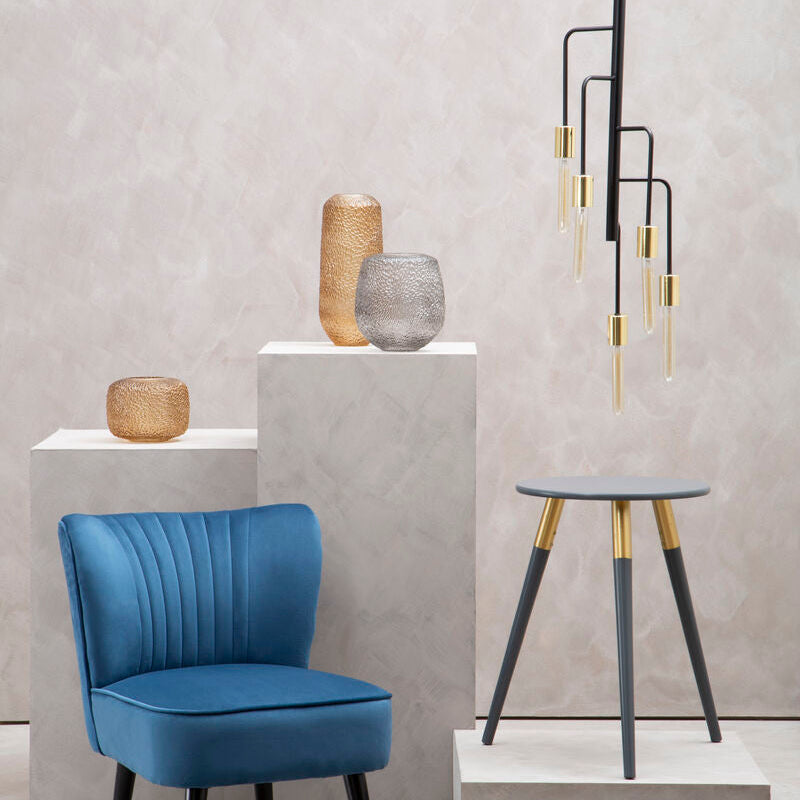 Blue chair and decorative items against a gray wall with a modern pendant light.