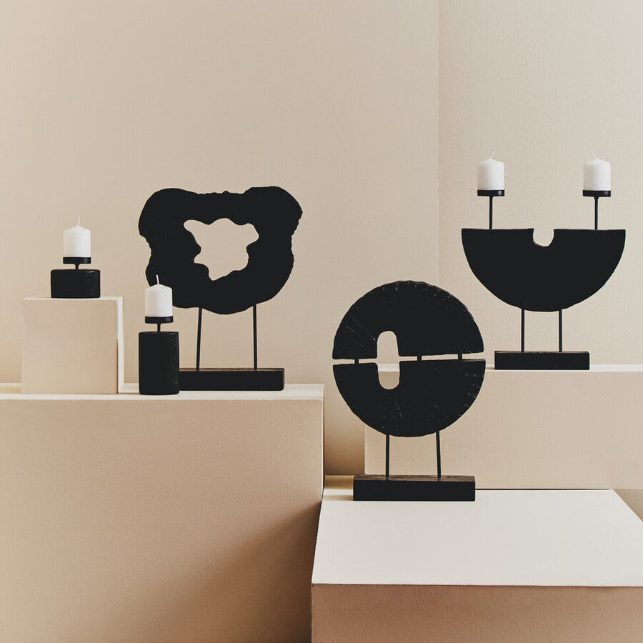 Decorative black sculptures with candles on a beige surface