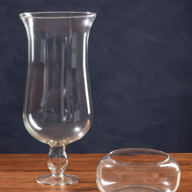 Two clear glass vases on a wooden surface with a dark background