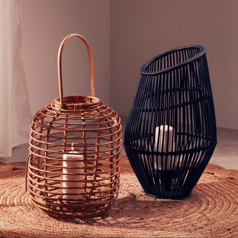 Two woven lanterns, one copper and one black, on a textured surface with a neutral background.