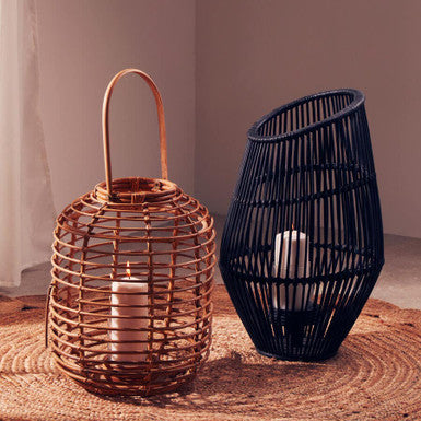 Two woven lanterns, one copper and one black, on a textured surface with a neutral background.