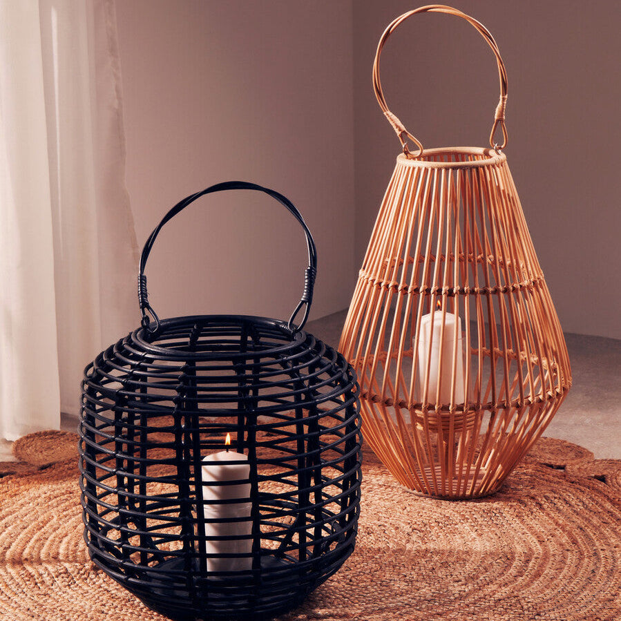 Two woven lanterns, one black and one copper, on a textured surface with a neutral background.