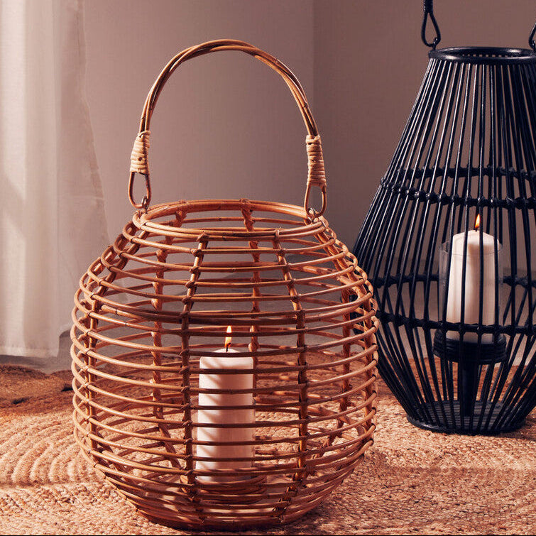Two lanterns, one woven and one metal, with candles inside on a textured surface.