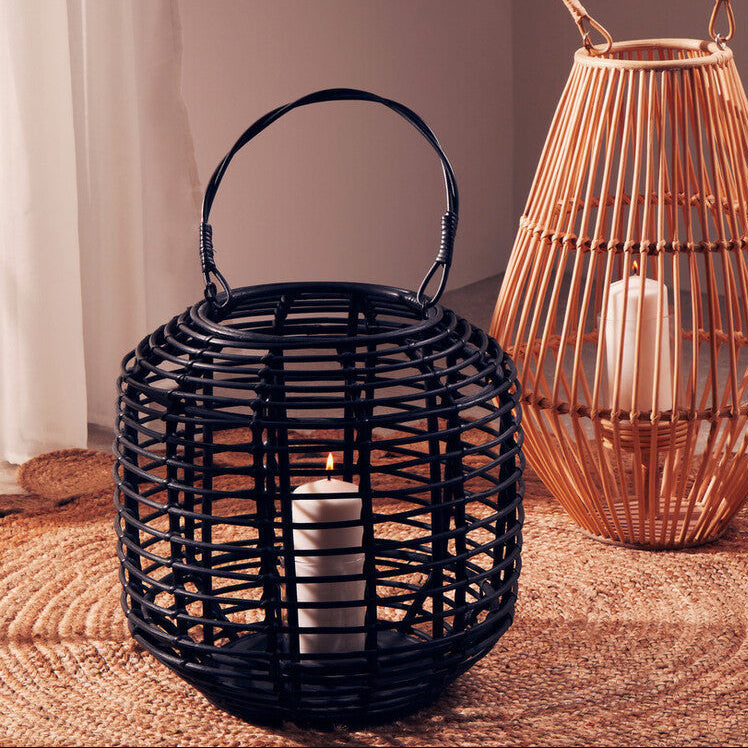 Two woven lanterns, one black and one copper, on a textured surface with a neutral background.