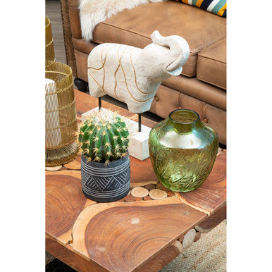 Decorative items on a wooden table including a green vase, potted cactus, and small sculpture.