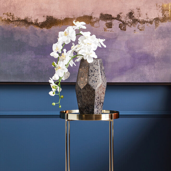 Decorative interior setting with a vase of white flowers on a small table against a blue wall.