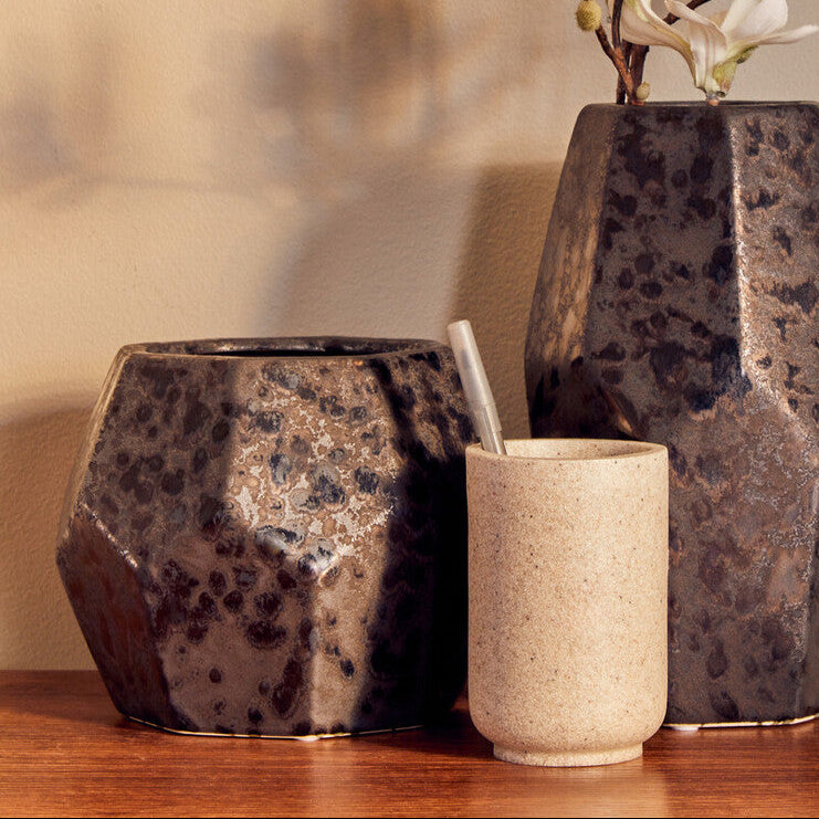 Three ceramic vases of different sizes on a wooden surface with a neutral background
