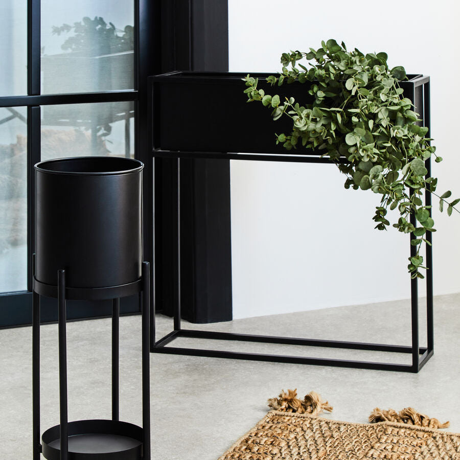 Black metal plant stand with a green plant indoors