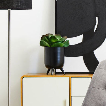 Gray armchair in a modern living room with abstract art and floor lamp.