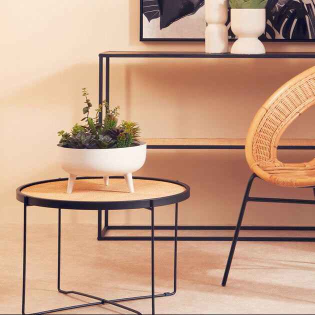 Wicker chair and small round table in a room with a wall art piece.