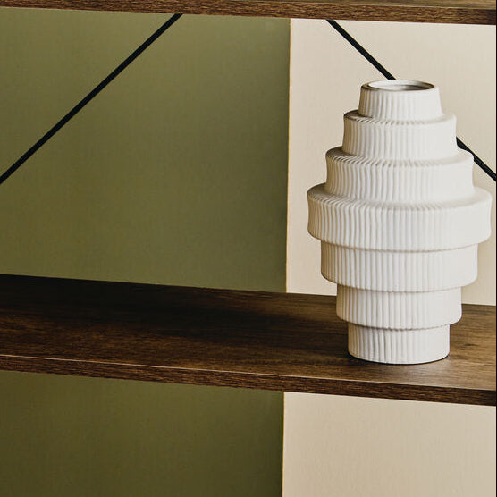 Wooden shelf with black metal legs against a green wall