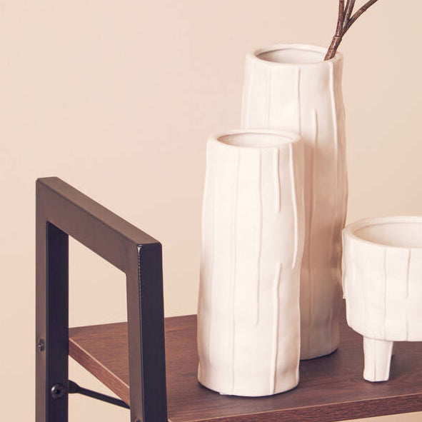 Two white ceramic vases on a wooden shelf with a beige background